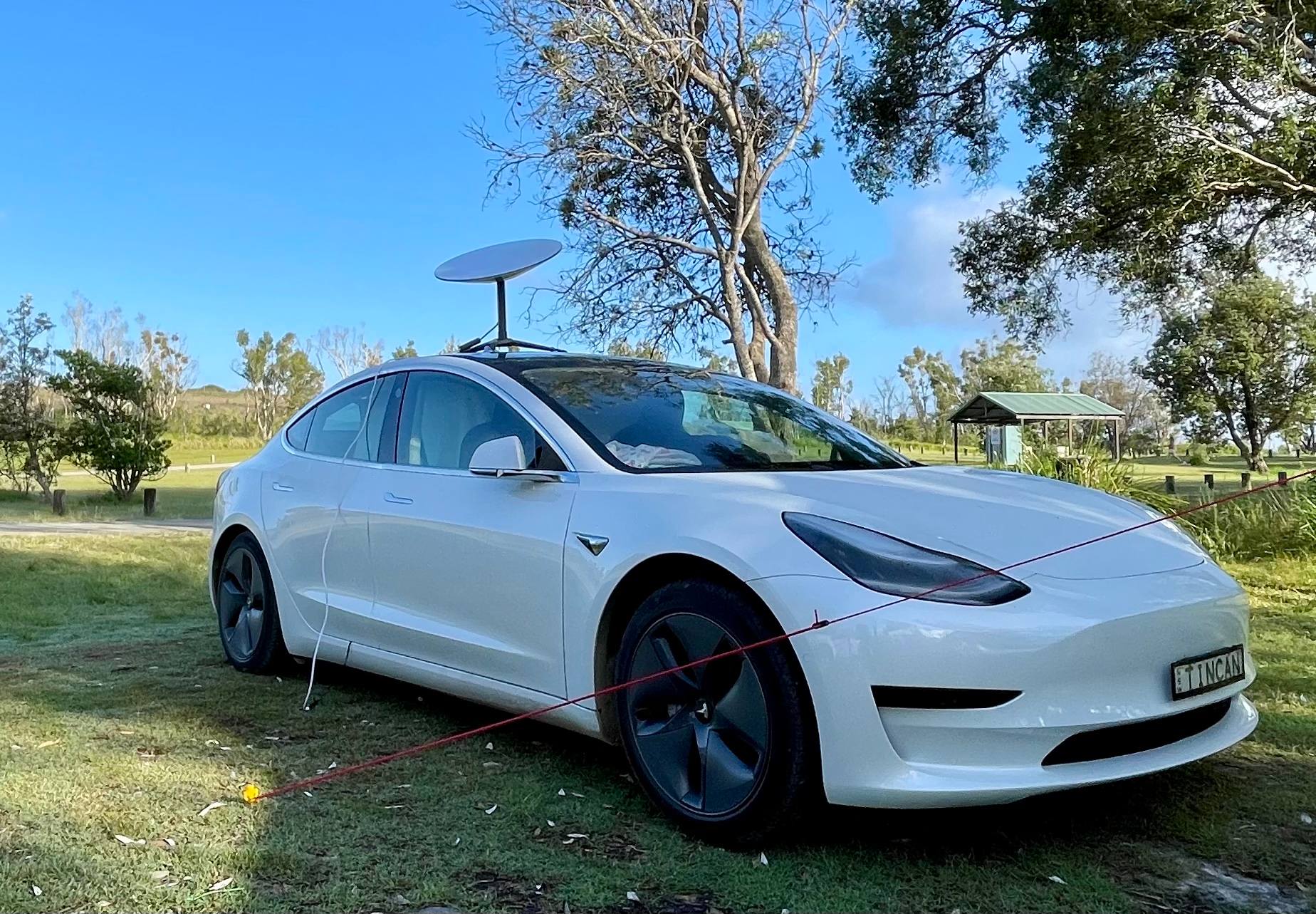 Tesla Model 3 and Starlink dish on top in a camp site