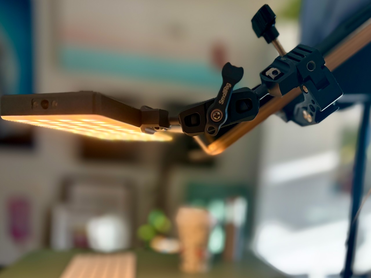 Small LED panel held beside a desk by a clamped articulating camera arm