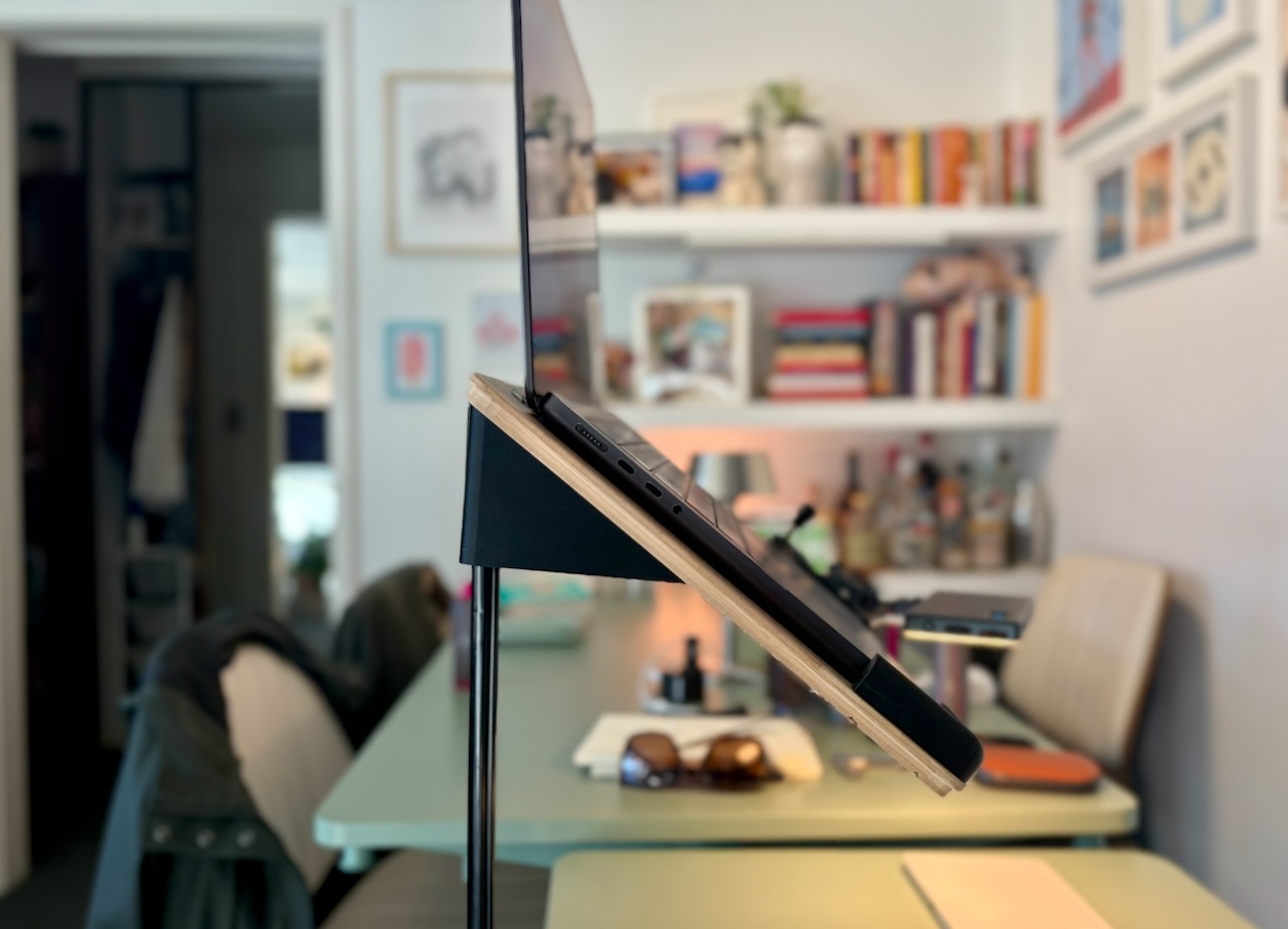 Laptop held at an angle on a slim camera-mount stand