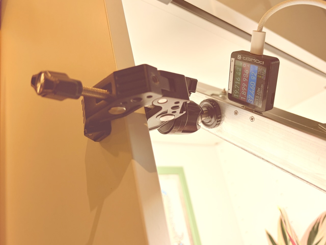 Large LED panel attached to a cabinet by a clamp, ball head and camera-mount hardware