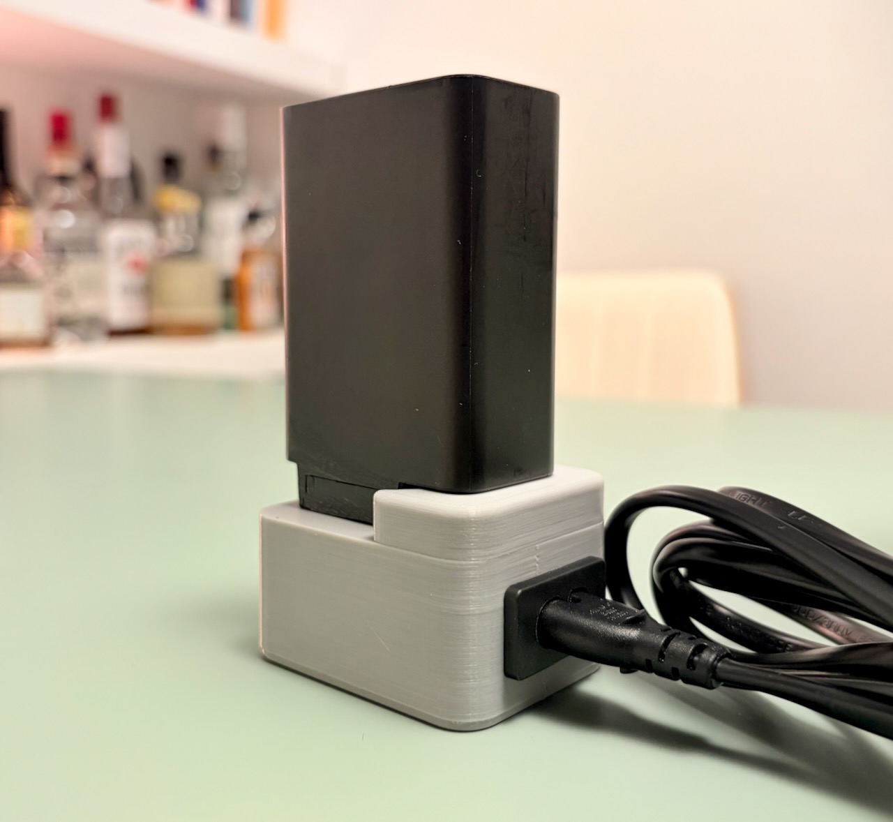 Large black wall charger supported in the 3D-printed adapter and powered by a figure-eight cable