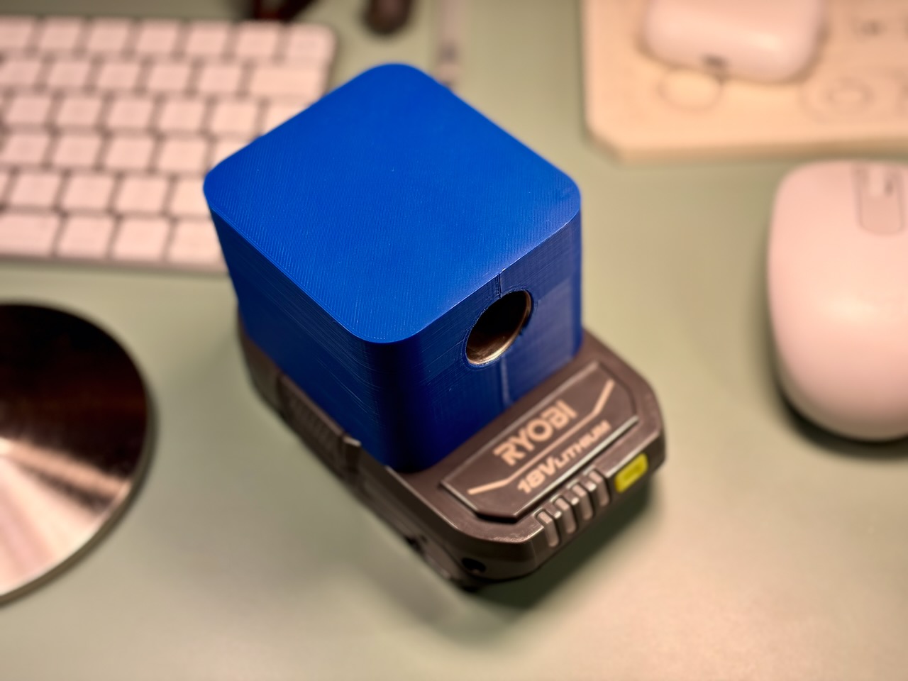 Blue 3D-printed cigarette lighter socket adapter attached to a Ryobi 18V ONE+ battery