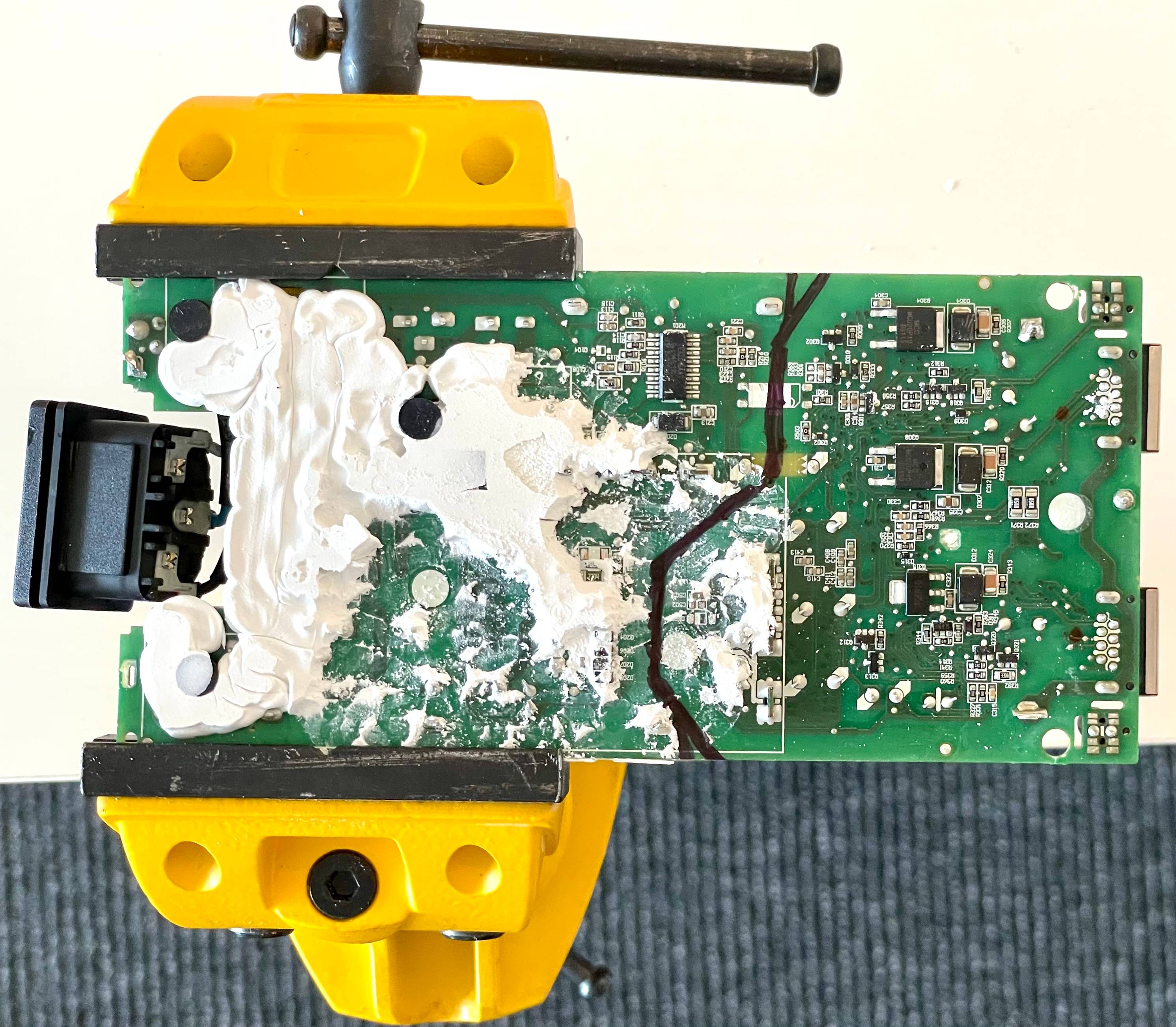 Bottom of the Starlink PSU PCB held in a jaw prior to cut