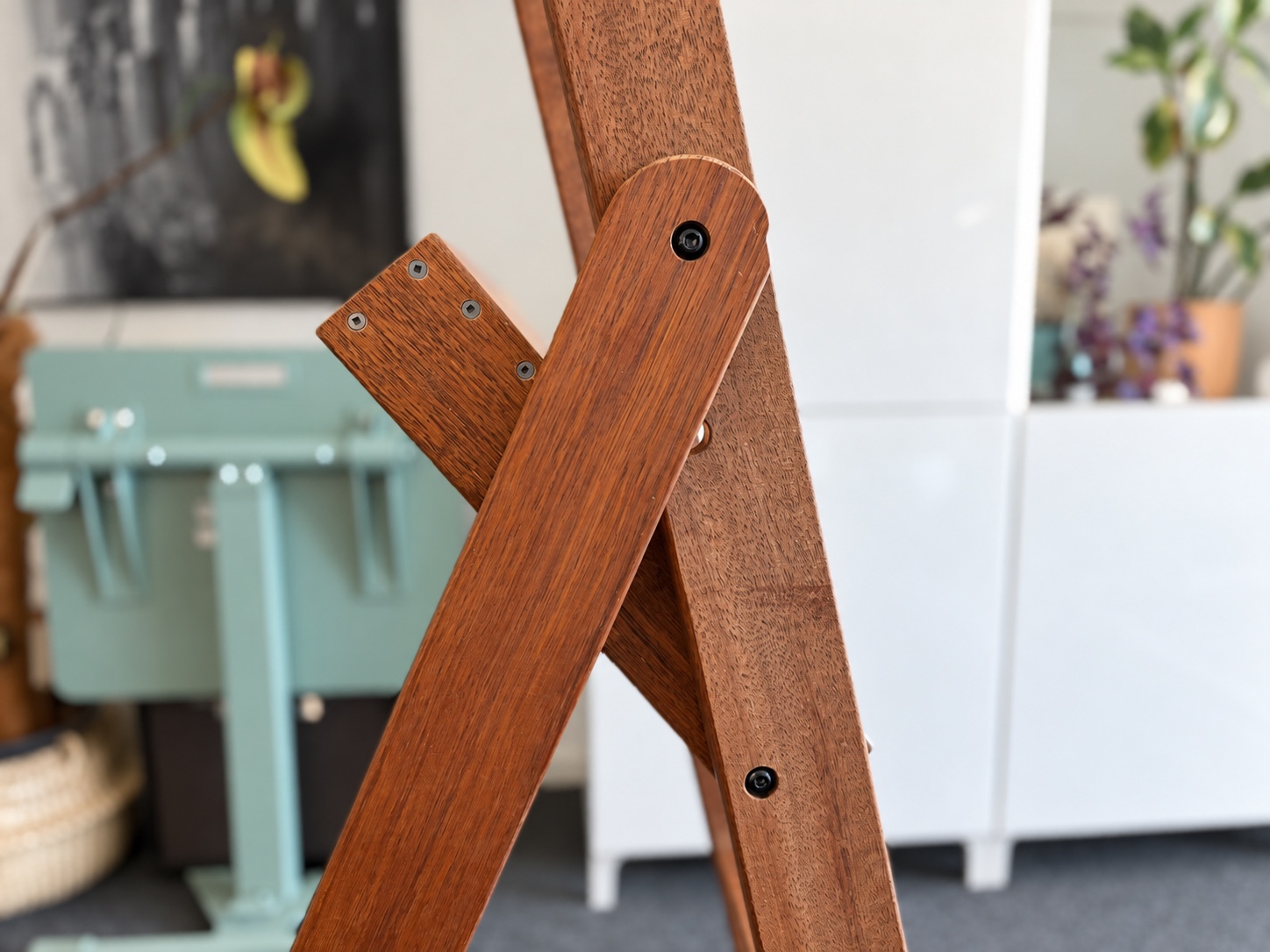 Rounded end of a rear leg around its black pivot bolt, with visible platform screws behind it