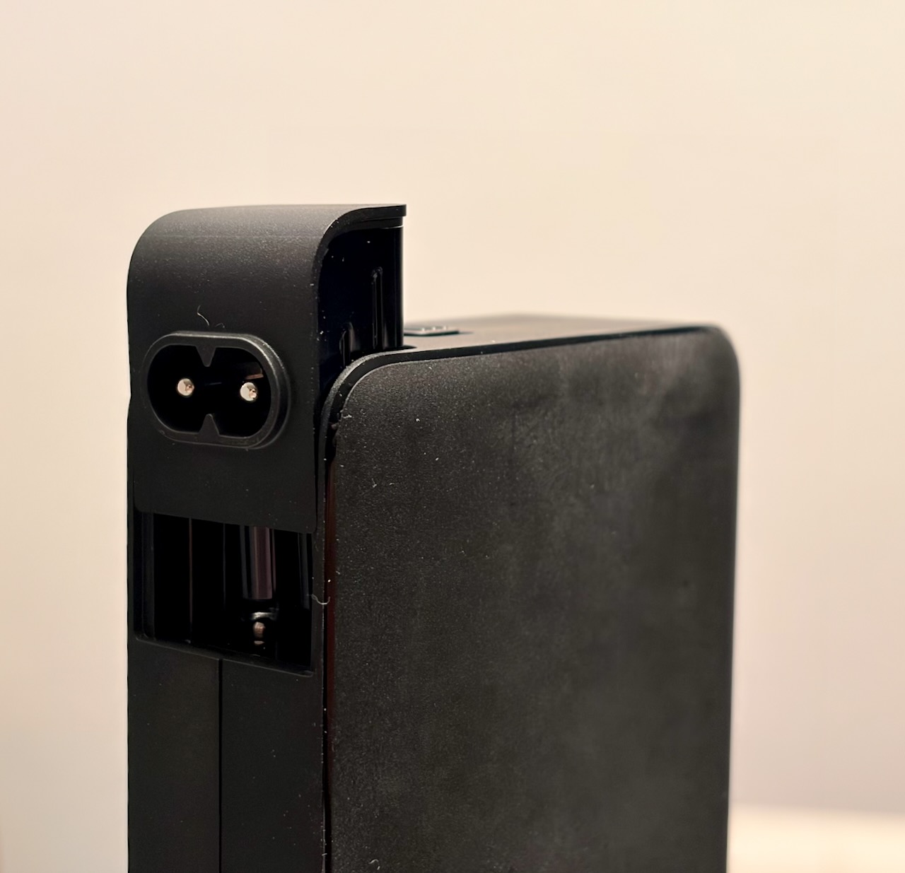 IEC C8 inlet head partly removed from the travel charger, exposing the proprietary ribbed connector behind it